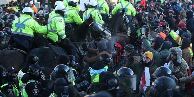 Horses are brought in to disperse the crowd in front of Parliament Hill in Ottawa, on Feb. 18, 2022.