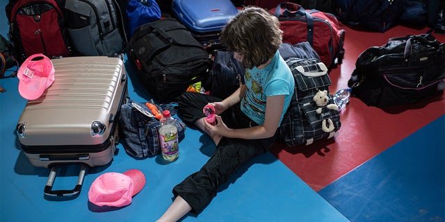 KYIV, UKRAINE - JUNE 20: A girl plays with a toy next to her and other childrens belongings on June 20, 2022 near Kyiv, Ukraine. The goal of the 7fields camp, which is near Zalissia National Nature Park, is to support the children of families displaced from other parts of Ukraine since the February 24 invasion, but who are remaining in the country. Over the summer, the camp aims to support 300 children between the ages of 7 and 15, with activities like swimming pools, tennis, soccer, yoga, chess and craft-making, in addition to therapy sessions. (Photo by Alexey Furman/Getty Images)