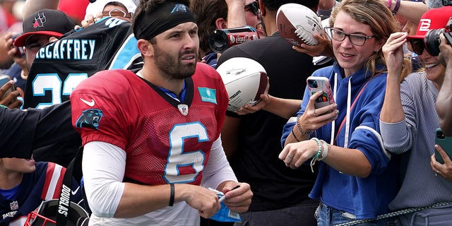 Carolina Panthers quarterback Baker Mayfield signs for fans after practice.