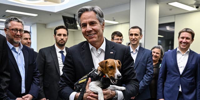 U.S. Secretary of State Antony Blinken (C) holds landmine sniffer dog, a Jack Russell Terrier named Patron during his visit at a children's hospital in Kyiv on September 8, 2022. - Secretary of State Antony Blinken on August 8, 2022, made a surprise trip to Kyiv as the United States unveiled nearly $2.7 billion in new military support to Ukraine and its neighbors to face Russia.