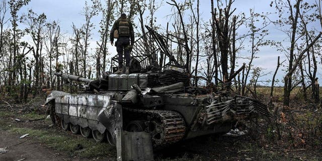 A Ukranian soldier stands atop an abandoned Russian tank near a village on the outskirts of Izyum, Kharkiv region, eastern Ukraine, on Sept. 11, 2022.