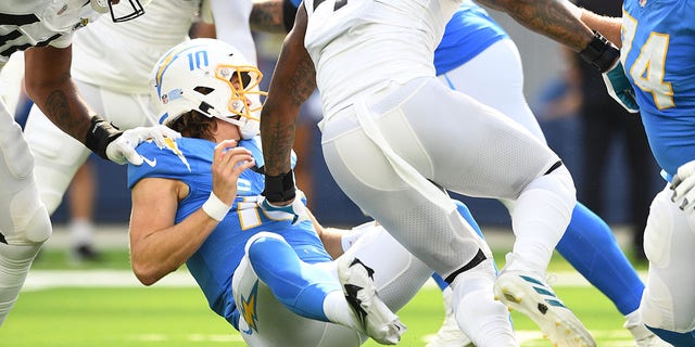 Los Angeles Chargers quarterback Justin Herbert, #10, is hit after throwing a pass during the NFL regular season game between the Jacksonville Jaguars and the Los Angeles Chargers on Sept. 25, 2022, at SoFi Stadium in Inglewood, California. 