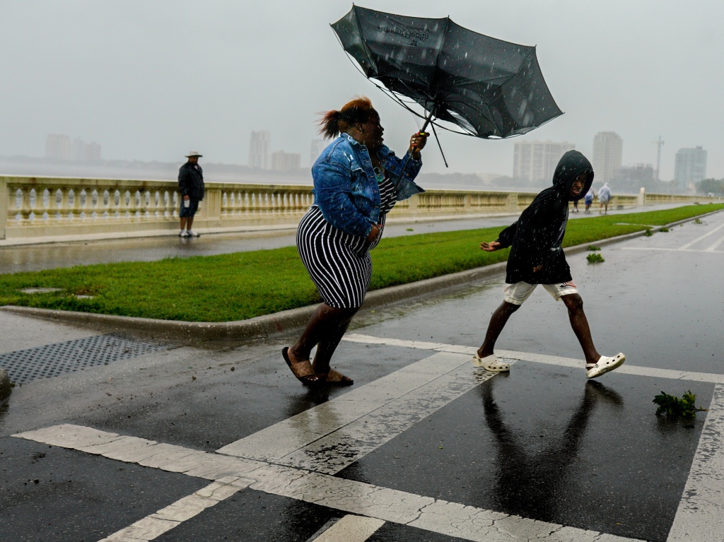 A woman holds an umbrella inverted by the wind in Tampa, Florida on Sept. 28, 2022. 