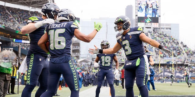 Tyler Lockett of the Seattle Seahawks (16) celebrates with Russell Wilson (3) after catching a touchdown pass during the second quarter against the Detroit Lions at Lumen Field on Jan. 2, 2022, in Seattle, Washington.