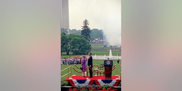 Queen Elizabeth II (left) and U.S. President George H.W. Bush (1925-2018) stand together as the former is welcomed on the White House South Lawn during a state visit May 14, 1991.