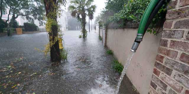 Residents use pumps to remove water from around their homes as the effects of Hurricane Ian are felt in Charleston, South Carolina, on Sept. 30, 2022.