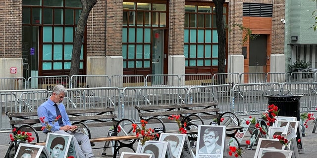 Nasser, president of the California Society for Democracy in Iran, sits in Dag Hammarskjold Park across from the U.N., surrounded by the photos of victims of the regime's "death commission."