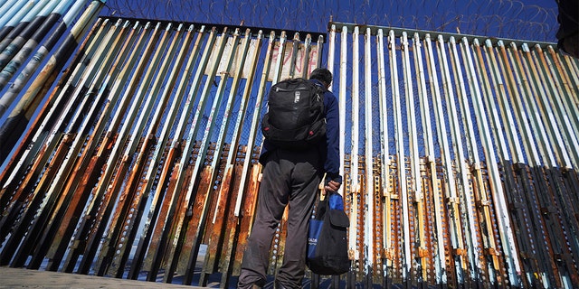 FILE: A migrant waits on the Mexican side of the border after United States Customs and Border Protection officers detained a couple of migrants crossing the US-Mexico border on the beach, in Tijuana, Mexico, Jan. 26, 2022.