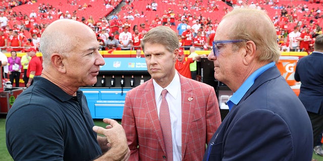 From left, Amazon founder Jeff Bezos talks with Kansas City Chiefs owner Clark Hunt and Los Angeles Chargers owner Dean Spanos on the field before the game at Arrowhead Stadium in Kansas City, Missouri, on Thursday.