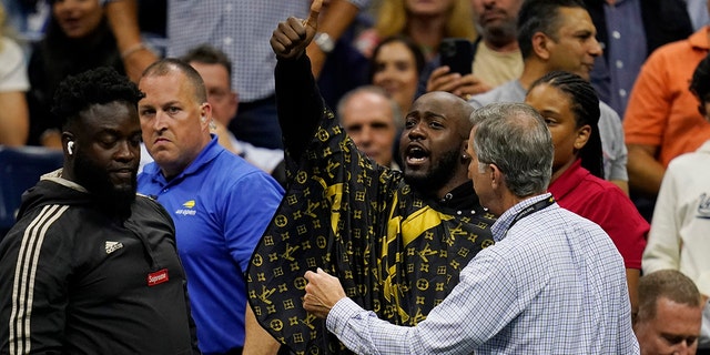 A fan, at center, gets removed from his seat after attempting to get a haircut during the quarterfinals of the U.S. Open tennis championships between Nick Kyrgios, of Australia, and Karen Khachanov, of Russia, Tuesday, Sept. 6, 2022, in New York. 