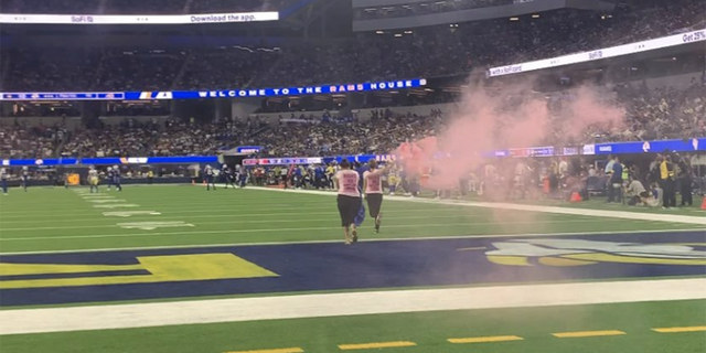 Two women rush SoFi Stadium field with smoke flares to highlight upcoming trial.