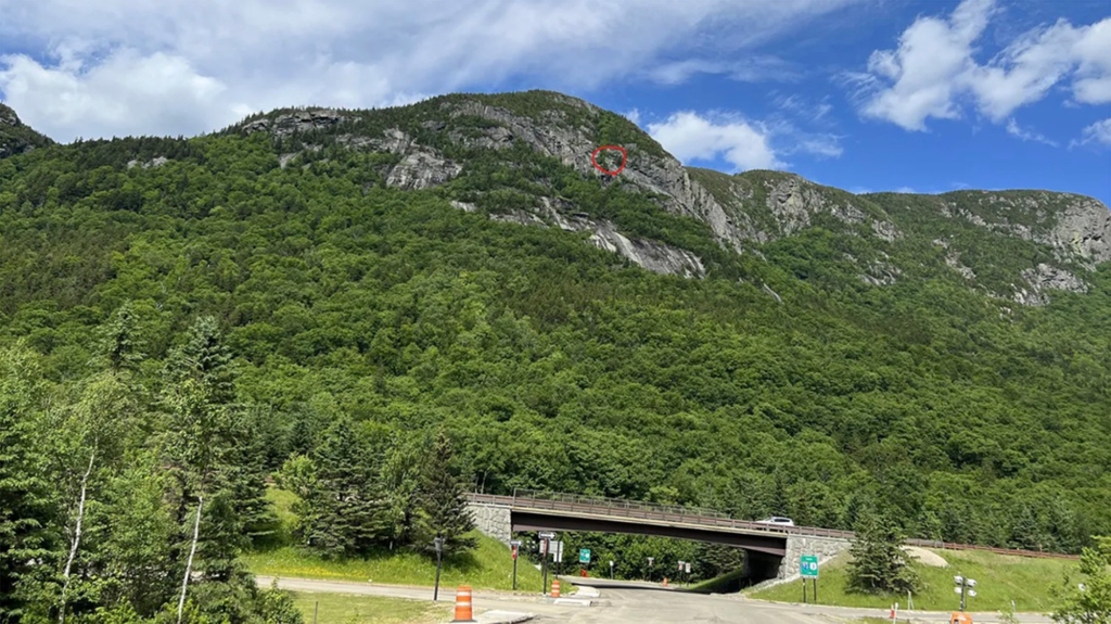 An image of a hiker on the side of Hounds Hump, a mountain in Franconia Notch State Park.