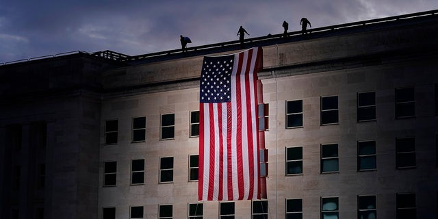 A large American flag is unfurled at the Pentagon ahead of ceremonies at the National 9/11 Pentagon Memorial to honor the 184 people killed in the 2001 terrorist attack on the Pentagon, in Washington, Friday Sept. 11, 2020.