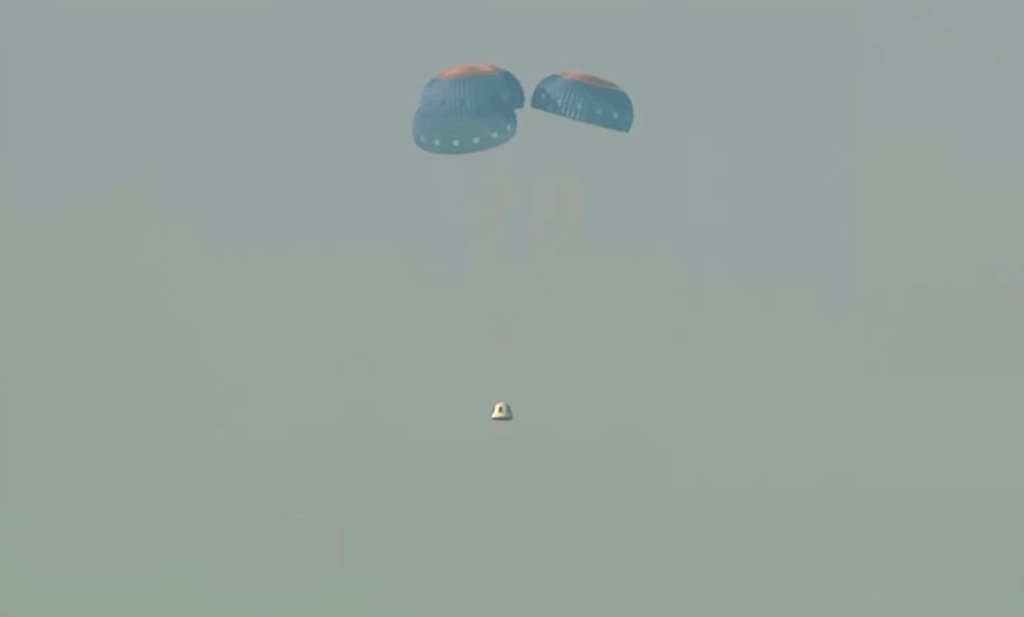 Capsule is shown parachuting onto the desert floor.