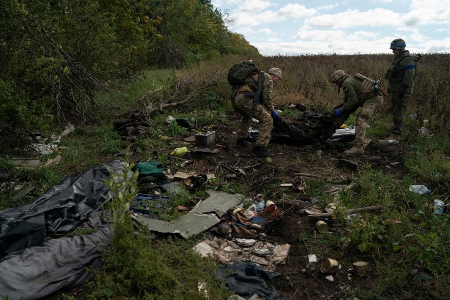 Ukrainian national guard servicemen place the body of a Ukrainian soldier in a bag at an area where three other bodies were lying on the ground in Ukraine.