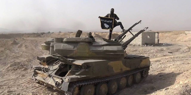 An ISIS militant stands on a tank captured from Syrian government forces, in Qaryatain, central Syria. (Photo released Aug. 5, 2015 by Rased News Network, a Facebook page affiliated with ISIS/via AP)