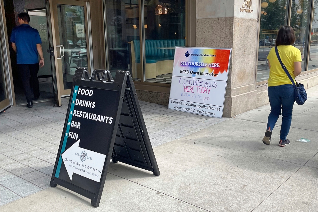 A Rochester City School District sign, right, announcing a recruitment event is posted outside the Mercantile On Main, in Rochester, NY, Wednesday, Aug. 17, 2022. Everywhere, it seems, the return to school has been shadowed by worries of a teacher shortage. 