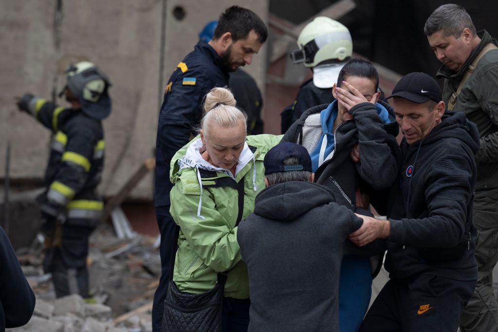 Relatives and friends comfort a woman after Ukrainian rescue workers found a body of a person under the debris following a Russian attack that heavily damaged a school in Mykolaivka.