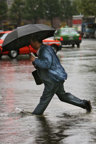 A man wades through a flooded road following overnight heavy rain .