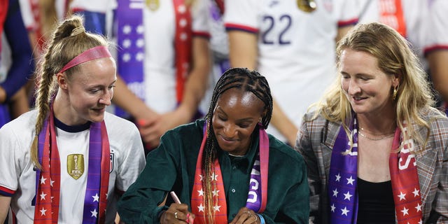 Crystal Dunn, center, signs a collective bargaining agreement providing equal pay for the U.S. men's and women's national soccer teams at Audi Field Sept. 6, 2022 in Washington, D.C.