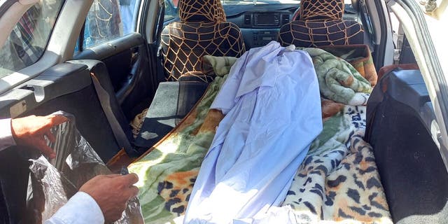 Covered body of a girl lies in the back of a vehicle after she was killed by unexploded shell in Helmand province, southern Afghanistan, Saturday, Sept. 3, 2022. Unexploded ordnance detonated Saturday in southern Afghanistan killing at least four children and injuring three others after the kids brought it inside their school, police and a doctor said