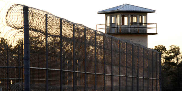 FILE - The sun sets behind Holman Prison in Atmore, Ala., on Jan. 27, 2022.