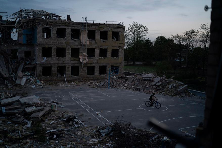 A man cycles through a courtyard of the destroyed School Number 23 after a Russian attack occurred in the second half of July, in Kramatorsk.