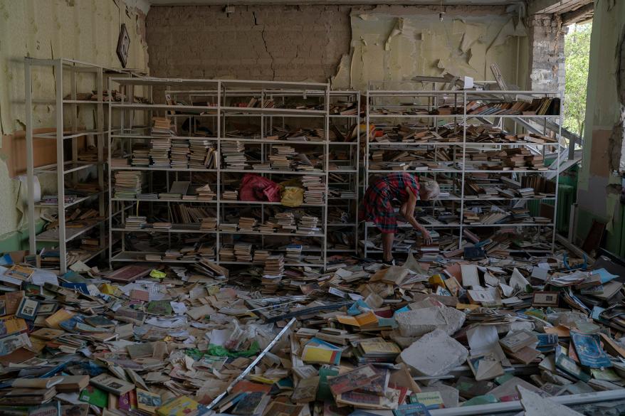 The librarian Raisa Krupchenko, 81, makes a pile of books as she tries to organize them among debris at the library of the destroyed School Number 23 after a Russian attack that occurred in the second half of July, in Kramatorsk.