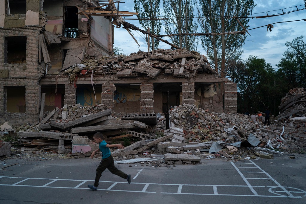 Oleksii Makarov, 6, runs past the building where his classroom was located as he plays in the courtyard of the destroyed school.