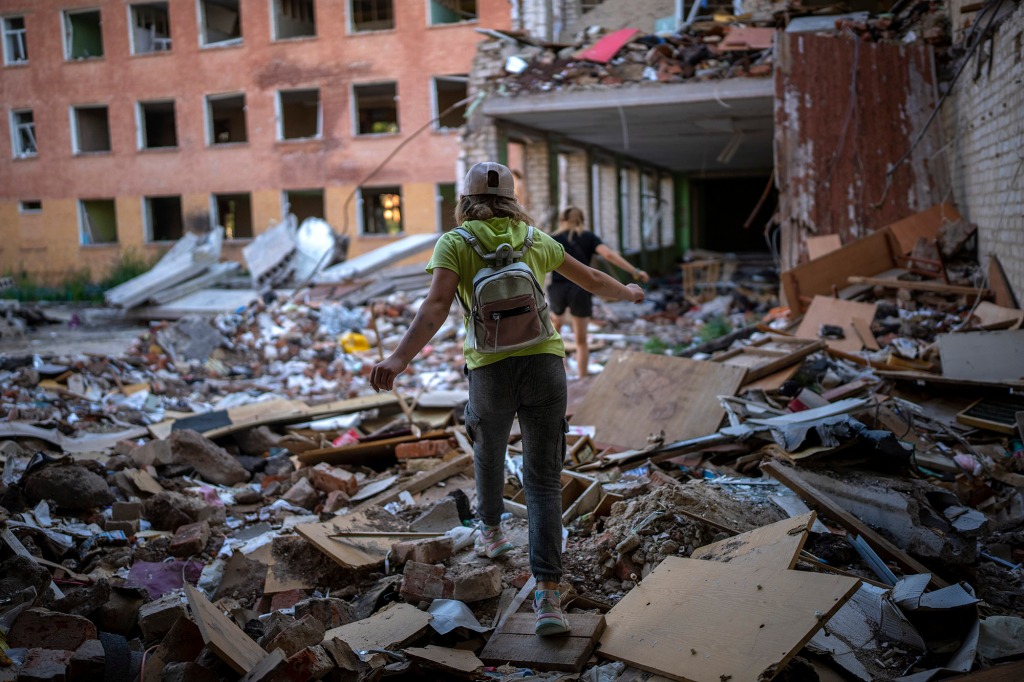 Student Karina Muzyka walks on the rubble of a school in Chernihiv.