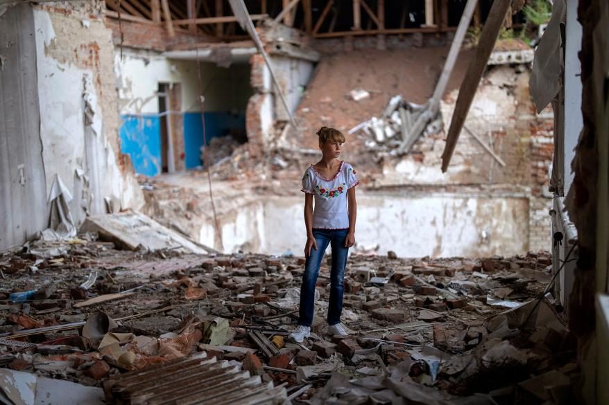 Sofia Klyshnia, 12, stands in the rubble of her former classroom, in the same position where her desk sat.