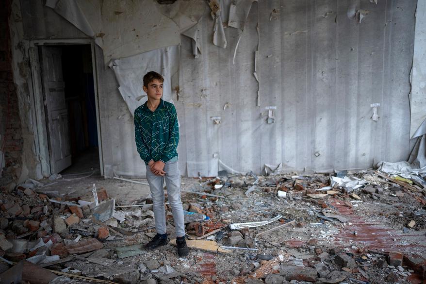 Oleksii Lytvyn, 13, stands in the rubble of his former classroom.