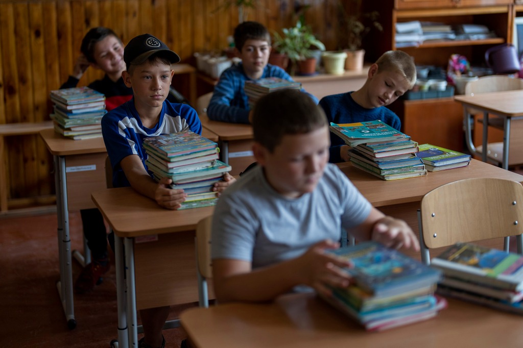 Students sit in a classroom to receive textbooks ahead of this week's beginning of the academic year at Mykhailo-Kotsyubynske's lyceum.