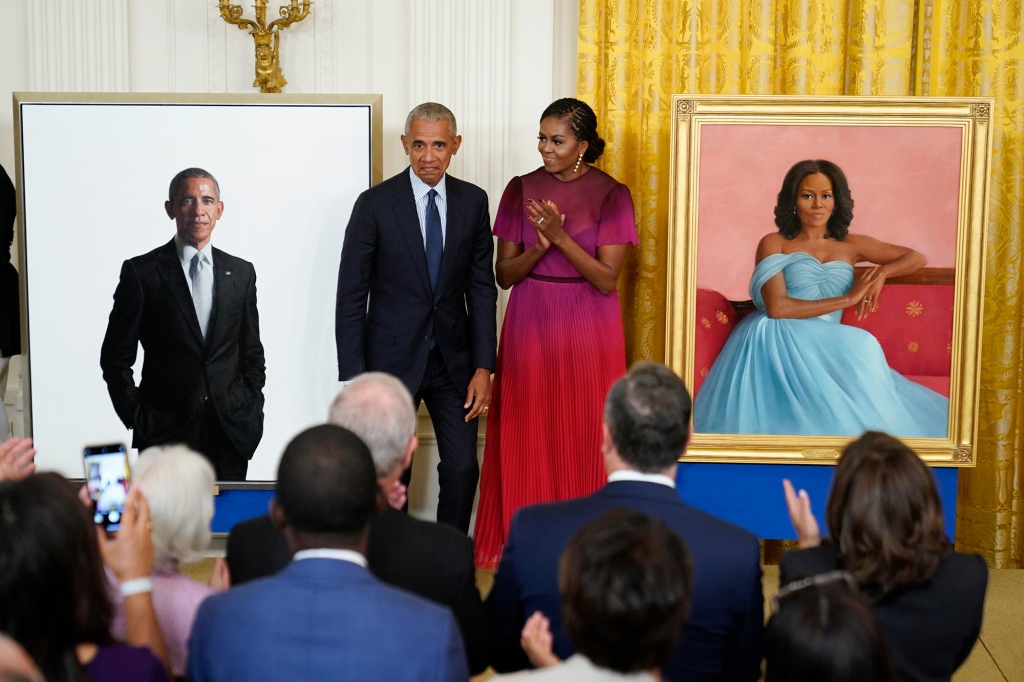 Former President Barack Obama and former First Lady Michelle Obama standing next to their White House portraits.