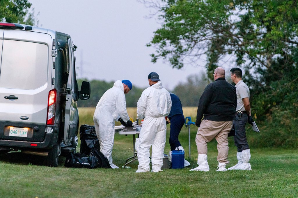 Investigators gather in front of a table near the scene of stabbing in Weldon, Saskatchewan on Sunday.