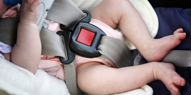 A file image of a baby in a car seat buckled up.