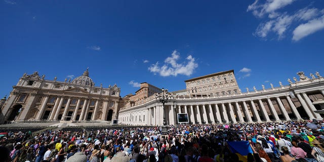 People gather as Pope Francis recites the Angelus noon prayer from the window of his studio overlooking St.Peter's Square, at the Vatican, Sunday, Sept. 11, 2022. 