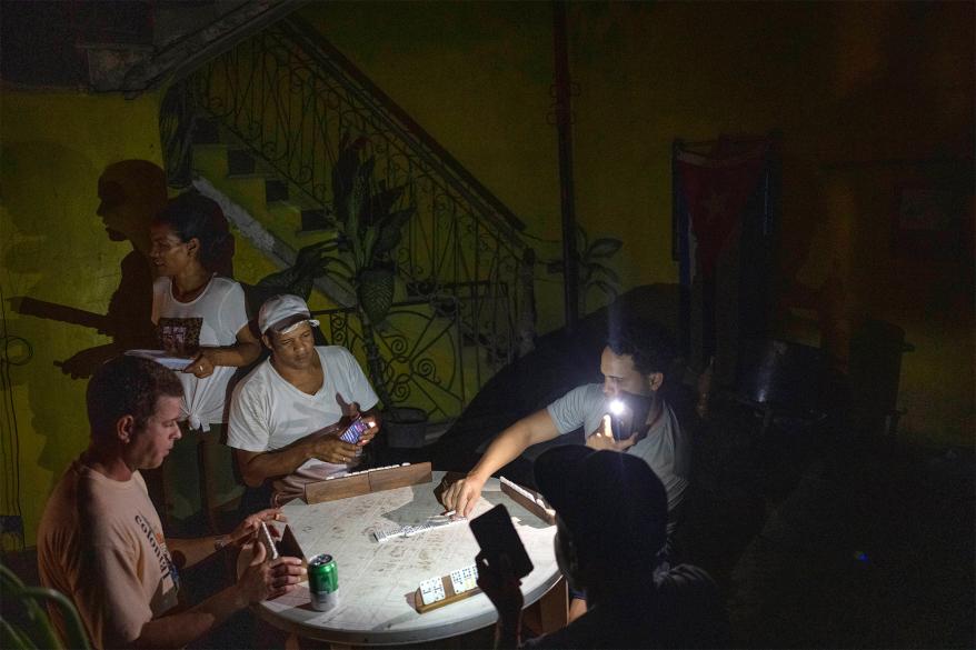 Cubans playing dominoes with a flashlight during the blackout following Hurricane Ian.