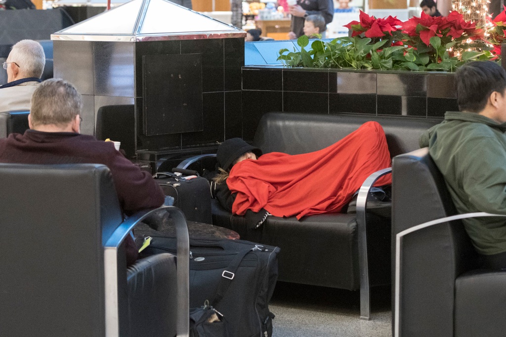 A woman rests as she and others wait in the terminal at Hartfield-Jackson Atlanta International Airport.