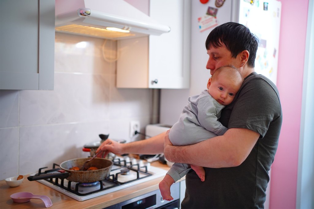 Man at stove holding baby