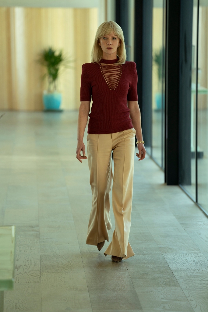 Gretchen Mol walking down a hall. 