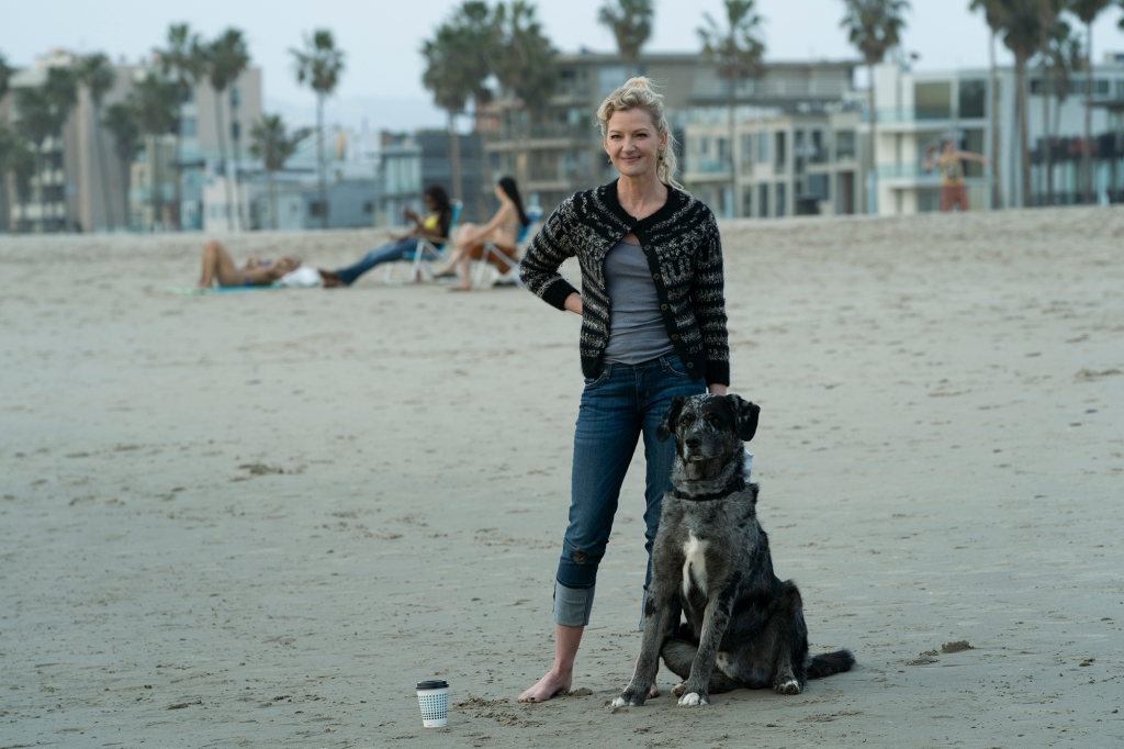 Gretchen Mol smiling on a beach with a dog. 