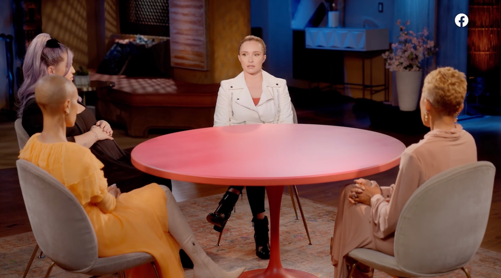 Hayden Panettiere sitting around a red table on "Red Table Talk" with hosts Jada Pinkett Smith and Adrienne Banfield Norris, and guest host Kelly Osbourne. 