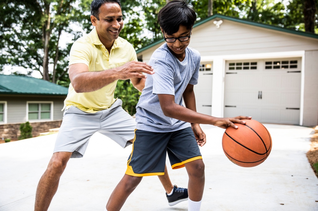 Father and son playing basketball in driveway