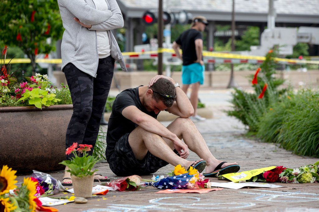 Mourners react at a memorial site for the victims of a mass shooting at a Fourth of July parade,