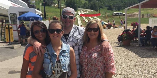 Taylor puts his arms around his mom and sisters in Utah.