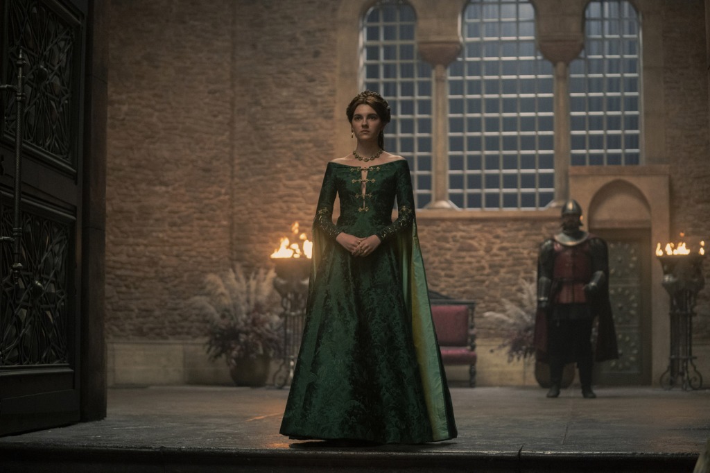 Alicent (Emily Carey) in a green dress standing in a doorway. 