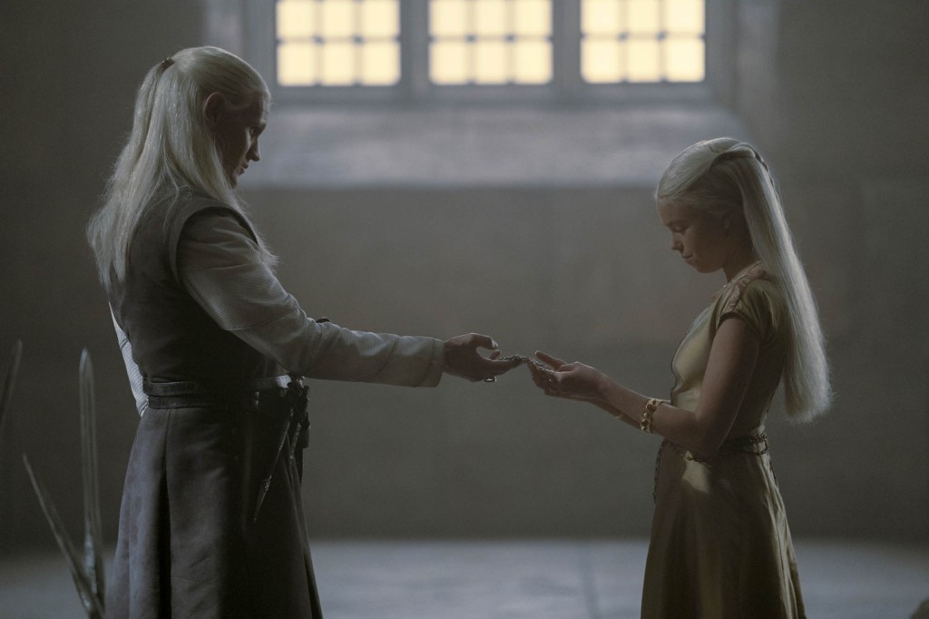 Daemon Targaryen (Matt Smith) and Rhaenyra Targaryen (Milly Alcock) on "House of the Dragon" face each other smiling in the throne room. 