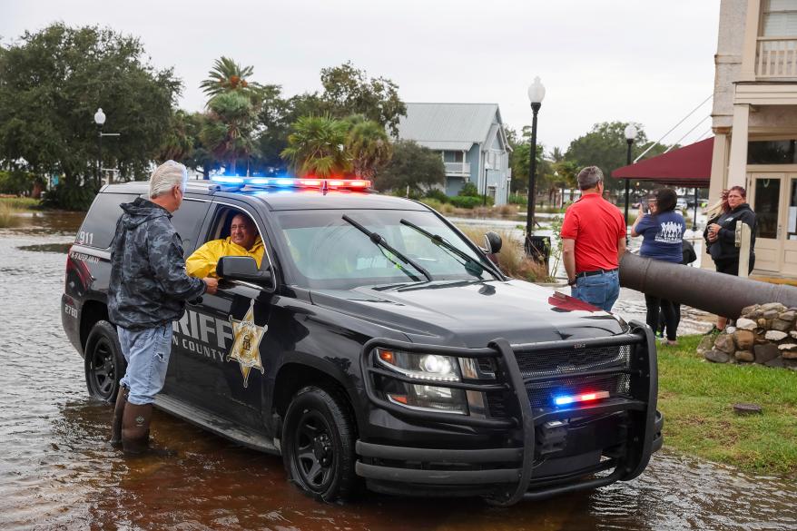 Citizens gather along flooded St. Marys Street during high tide in St. Mary's, Ga., on Thursday, Sept. 29, 2022. Tropical Storm Ian is heading north from Florida. (Arvin Temkar/Atlanta Journal-Constitution via AP)
