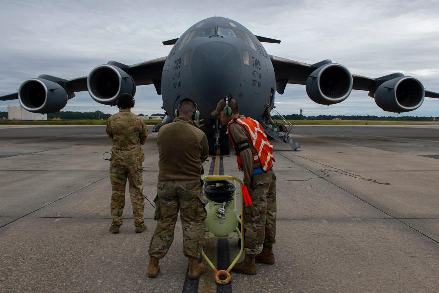 U.S. Air Force Airmen 1st Class Justin Carrizales and Natanaell Vicente-Castro, 437th Aircraft Maintenance Squadron crew chiefs, speak to each other during C-17 Globemaster III relocation operations for Tropical Storm Ian at Joint Base Charleston, South Carolina, Sept. 29, 2022